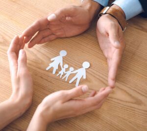 Family made out of paper encircled by 2 pairs of hands representing family law